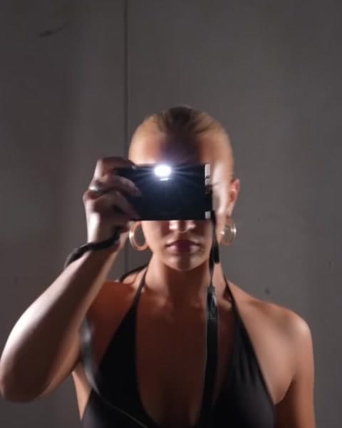 A woman lit by the flash of the camera she's holding