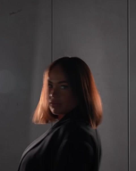 A woman with a copper bob between two studio lights